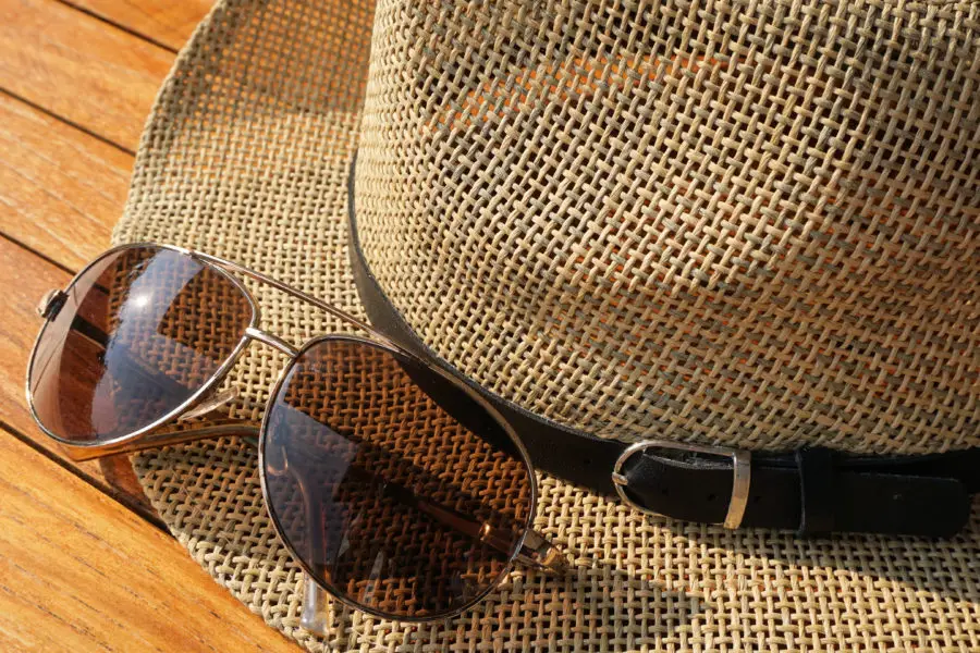 Brown straw hat beside brown aviator sunglasses.