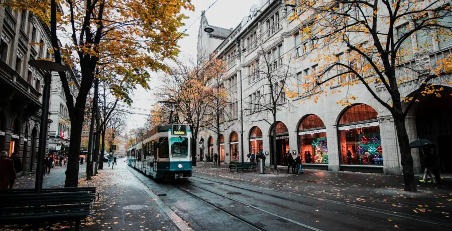 Train on street in Europe, surrounded by trees with colorful, autumn leaves