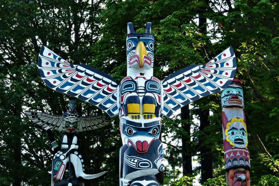 Three totem poles and the forest in Stanley Park, Vancouver, a beautiful sight on your Vancouver walking tour