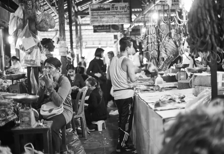 A black and white photo of some people visiting and manning the food stalls in the Siem Reap Old Market