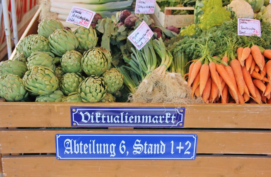 A stall selling vegetables at Viktualienmarkt Munich, including carrots and green onions - a stop on our free walking tour of Munich