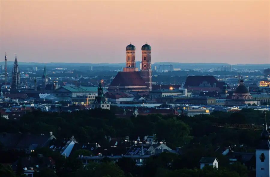 A view of Frauenkirche and the Munich skyline at dusk, with the sky orange, pink, and violet - a must-see sight even if you only have 1 day in Munich
