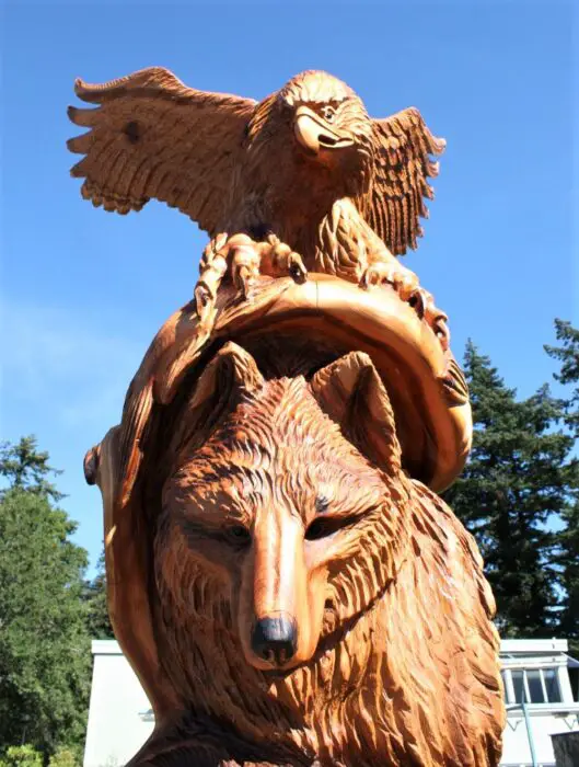A chainsaw wooden carving of an eagle standing on top of a beam over a wolf, one of the best things to do in Hope BC