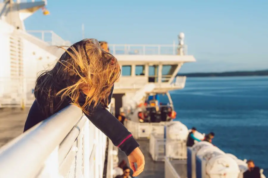 A girl leaning on a white rail on the second story of a BC ferry heading to Campbell River British Columbia