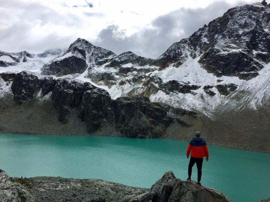 A man in a red and blue jacket at the turquoise Wedgemount Lake, one of the top hiking Squamish spots