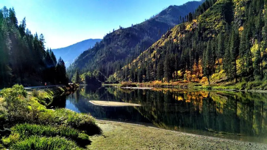 A small clear pond surrounded by colorful trees and tall mountains near Leavenworth WA on a sunny day