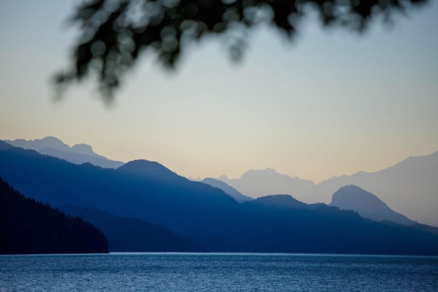 Distant light blue British Columbia mountains and the deep blue Harrison Lake at dusk