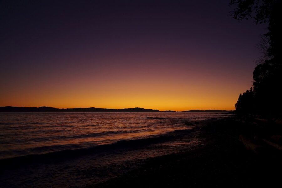 Late sunset from one of the beaches on the Sunshine Coast, the small waves in the water dark and most of the sky a deep violet shade