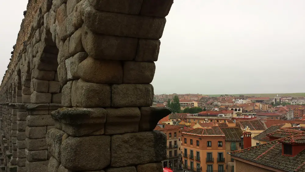 Photo from the top of the Segovia Aqueduct with views of the town of Segovia on an overcast day. The Aqueduct is the first stop on our Segovia free walking tour.