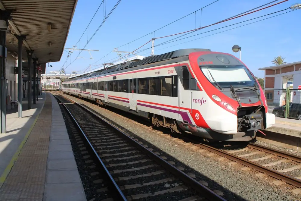 Photo of a red and white Renfe train in Spain stopped at a train station.