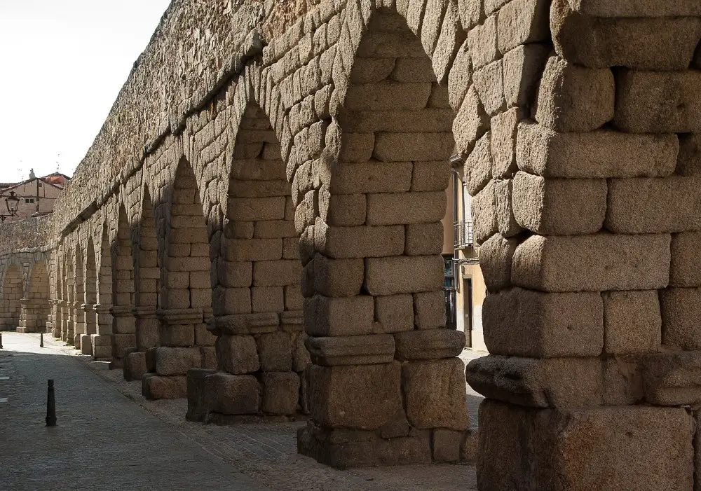 Photo of the Aqueduct of Segovia at one of its far ends, with no tourists around and the arches closer to the ground.