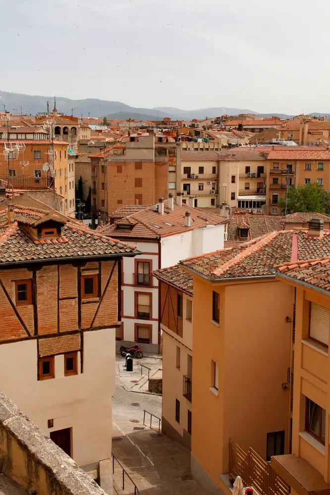 Photo from a balcony of the orange, tan, and white buildings of Segovia on an overcast day.