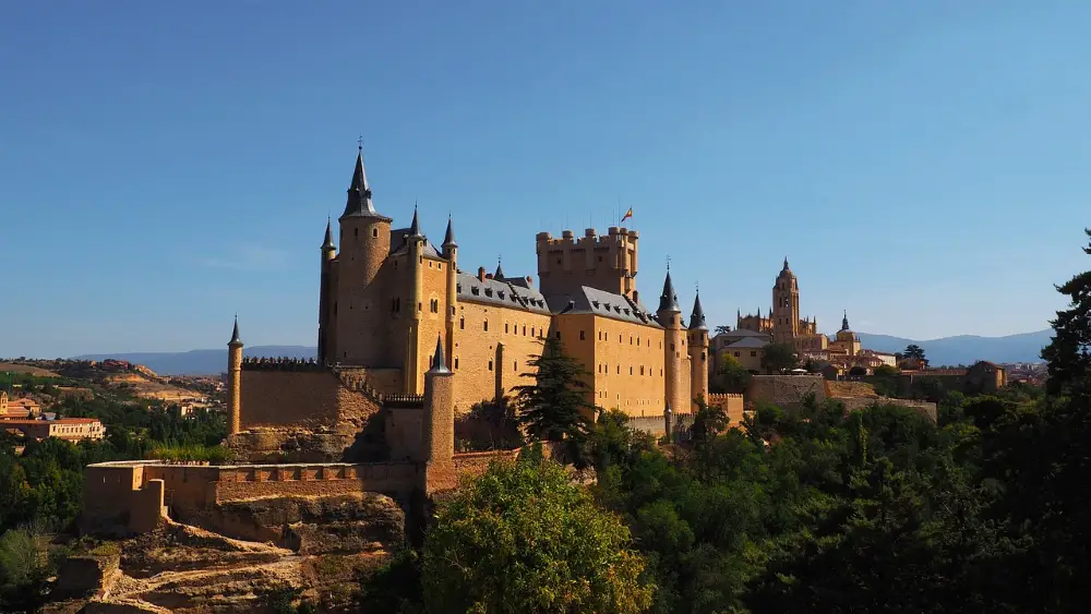 Photo of the Segovia Alcazar with a focus on its ship-lake shape, with the Segovia Cathedral visible in the background.
