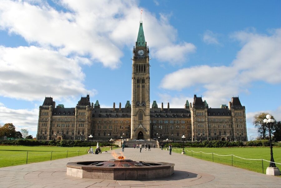 A full, frontal view of the Peace Tower, Centennial Flame, and the main Parliament Building on Parliament Hill, Ottawa