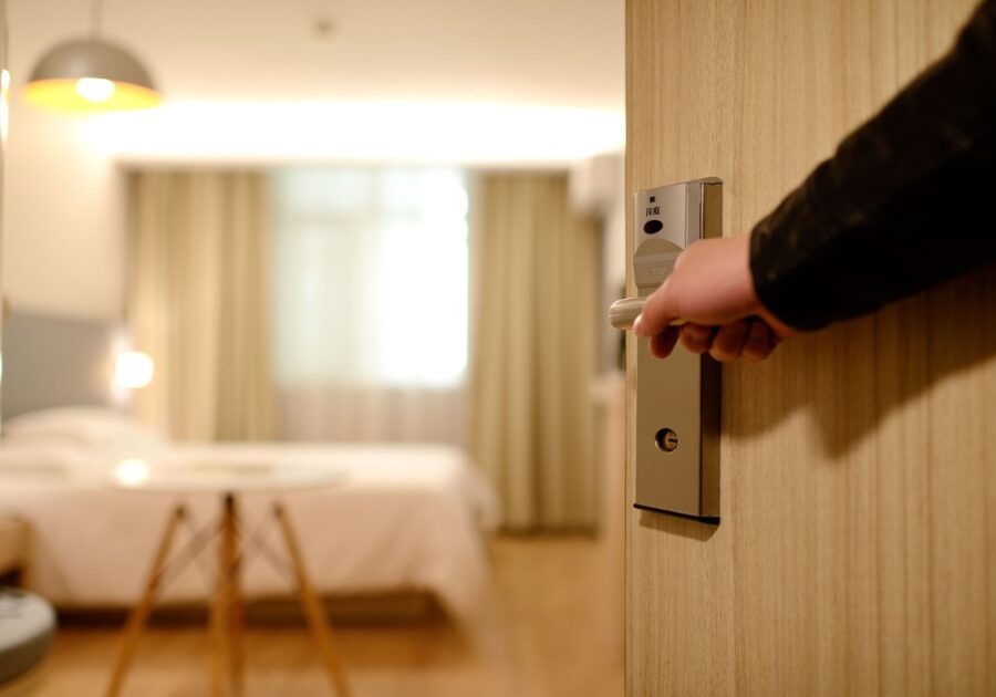 A hand opening the door to a modern and comfortable hotel room in Seville Spain.