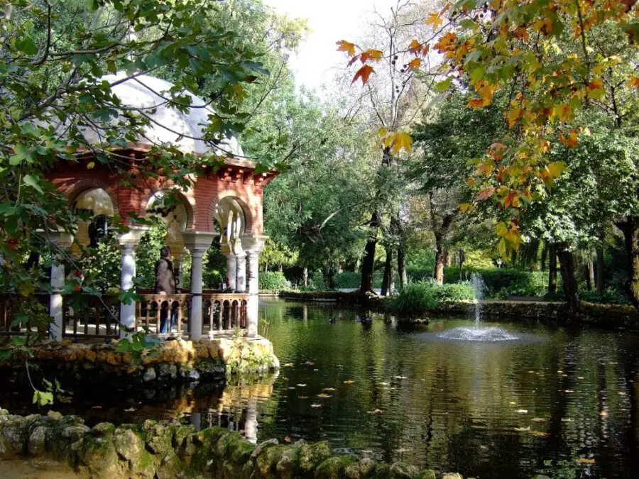 A pond, fountain, and pink gazebo in Maria Luisa Park on a sunny day, the first stop on our walking tour of Seville.
